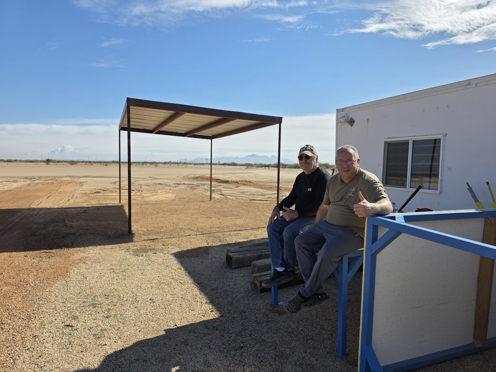 Two club members giving a thumbs-up at the field during the pit area rock project